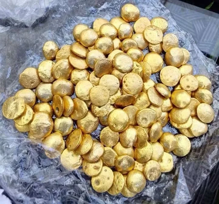 Rounded gold-coloured pieces resting on clear plastic